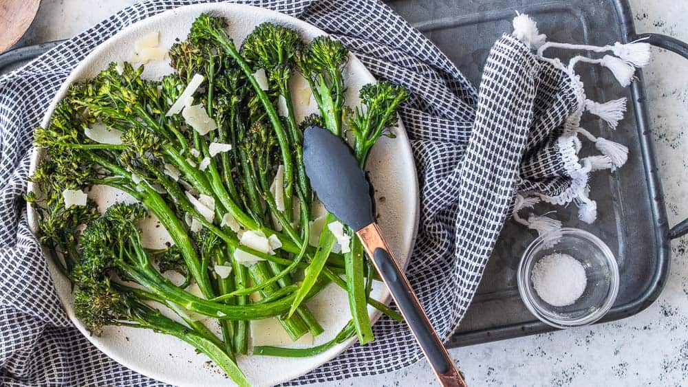 top down view of air fryer broccolini topped with grated parmesan cheese