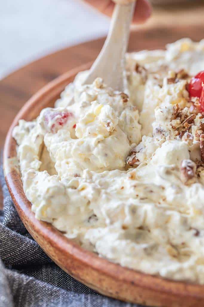 close up of wooden spoon scooping pineapple fluff from bowl