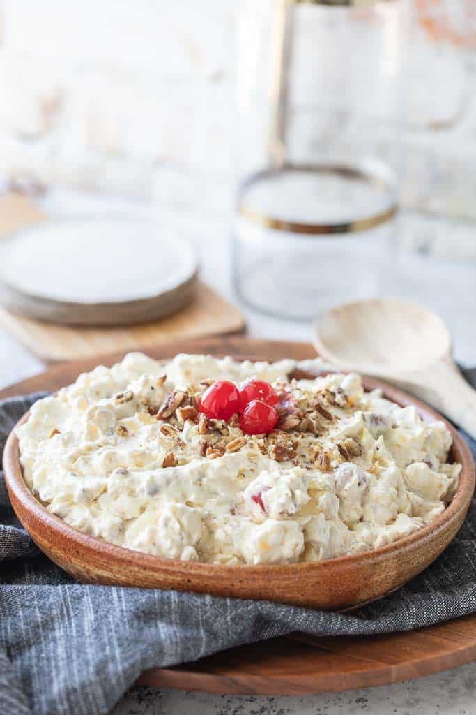 pineapple fluff in bowl topped with crushed pecans and cherries