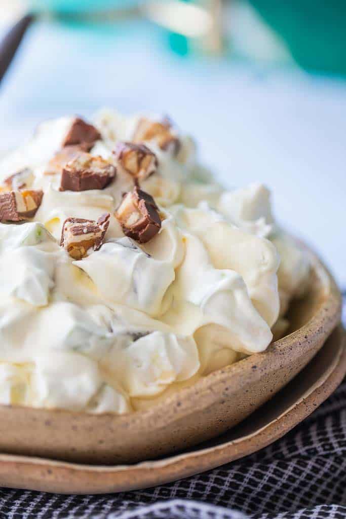 creamy taffy apple salad in bowl topped with chopped snickers
