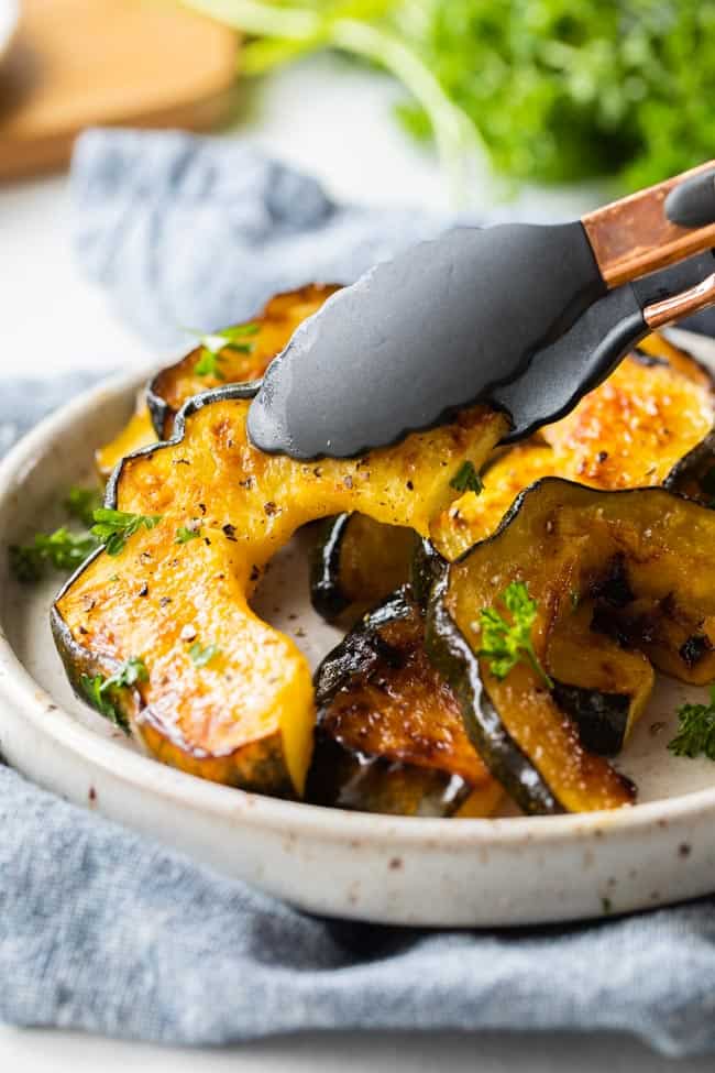 tongs picking up slice of acorn squash