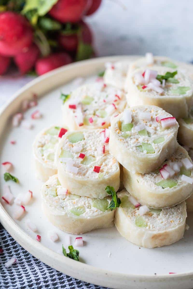 creamy chicken pinwheels stacked on a plate garnished with minced radishes