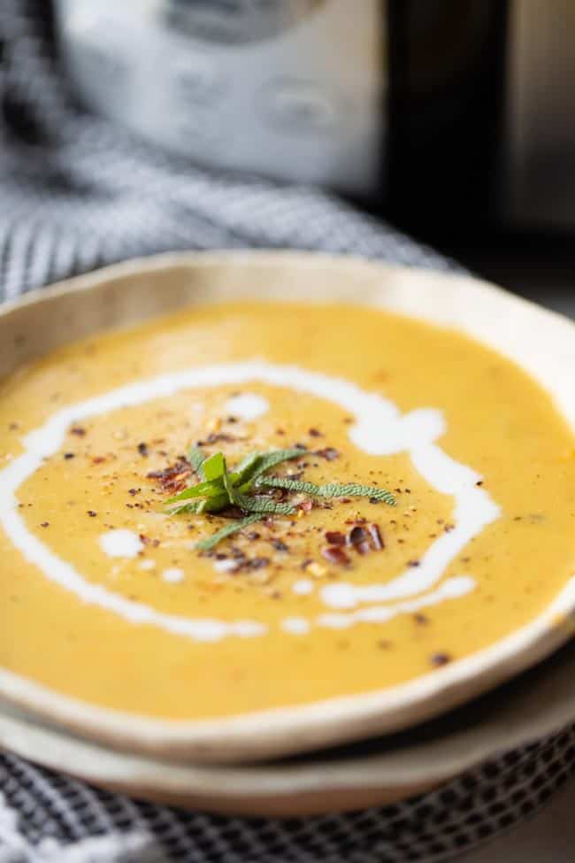 creamy soup in bowl garnished with coconut milk swirl and red pepper flakes