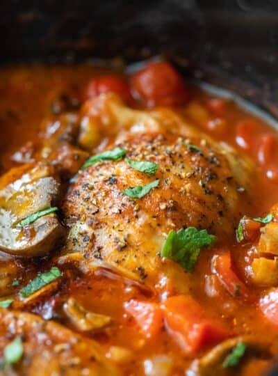 close up view of chicken thigh in tomato sauce in crockpot
