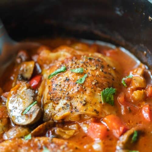 chicken thighs submerged in tomato and mushroom sauce in crockpot