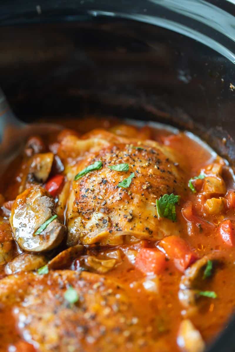 chicken thighs submerged in tomato and mushroom sauce in crockpot