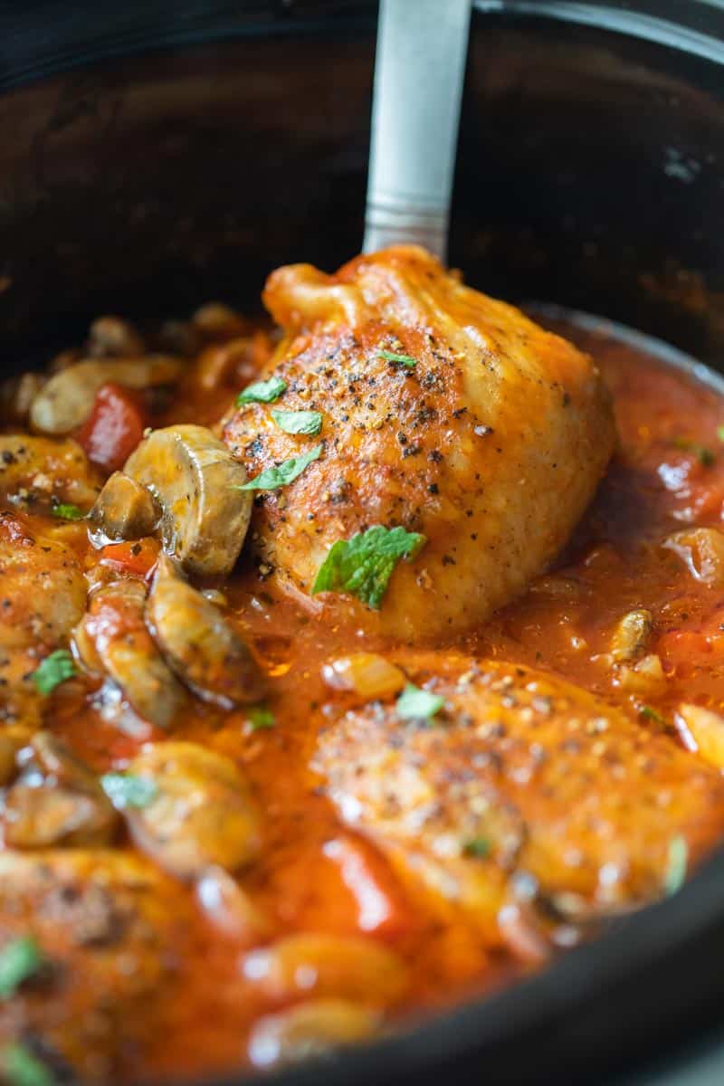 ladle scooping chicken thigh from slow cooker