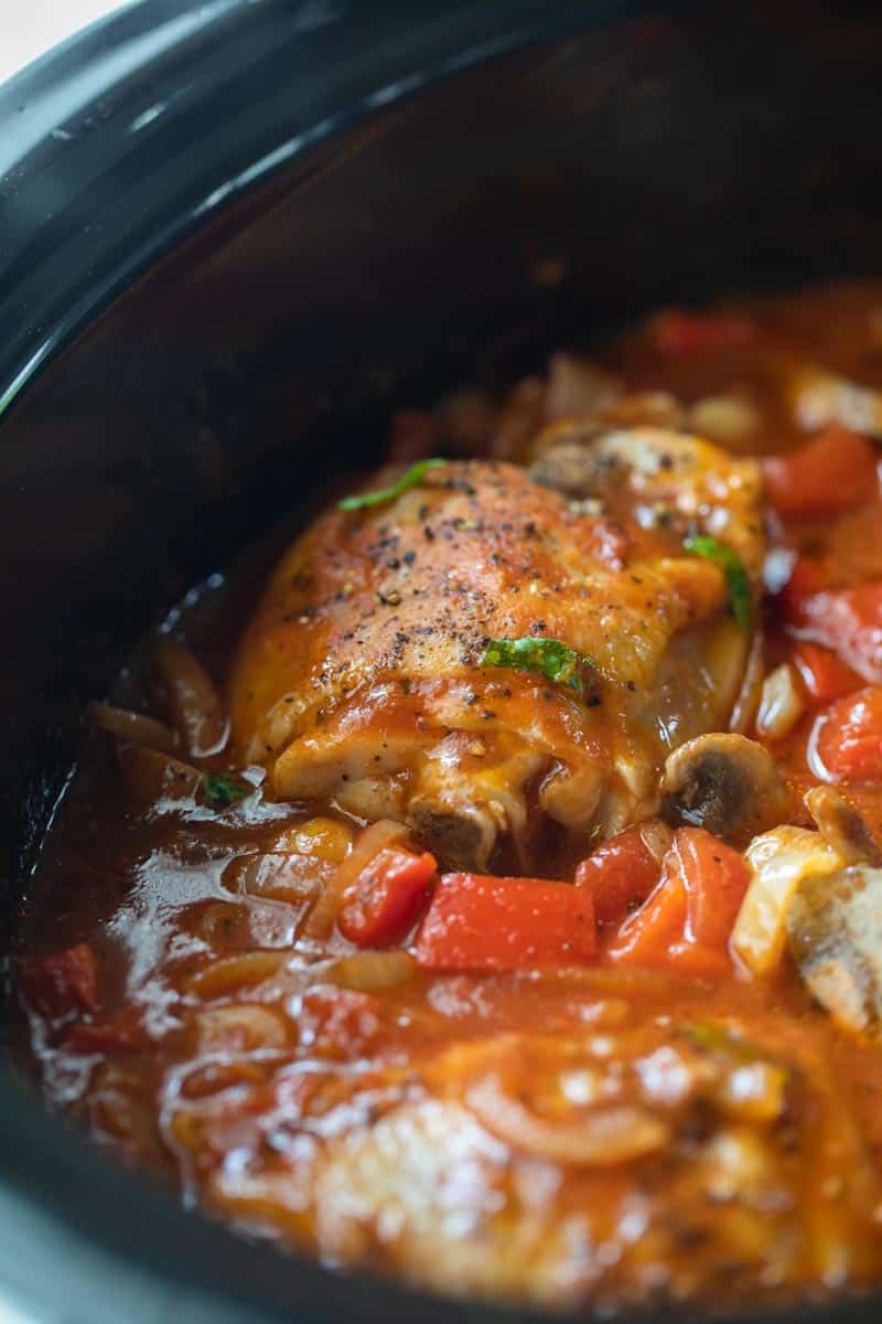 chicken thighs submerged in tomato sauce in crockpot