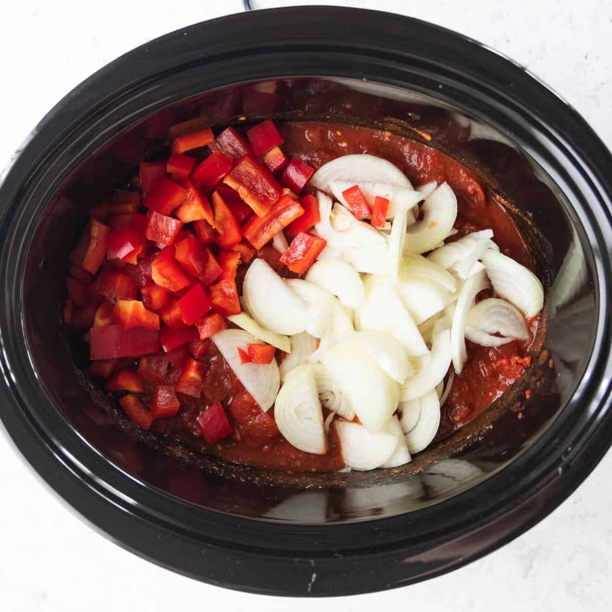 diced red peppers, sliced onions and tomato sauce in slow cooker