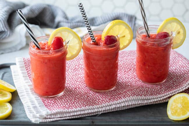 three mason jars with straws filled with strawberry lemonade