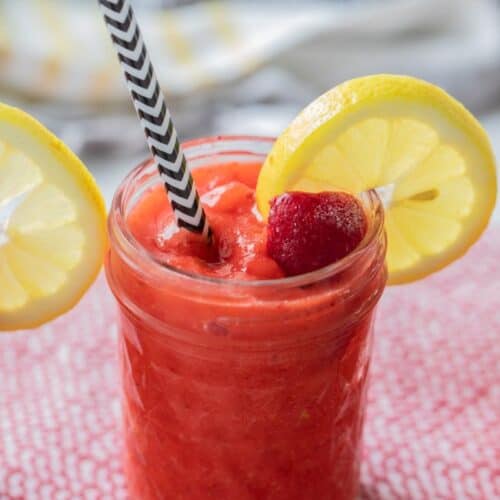 straw in a mason jar filled with red strawberry lemonade