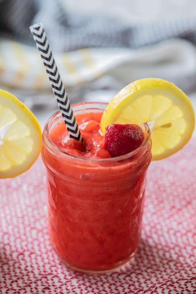 straw in a mason jar filled with red strawberry lemonade