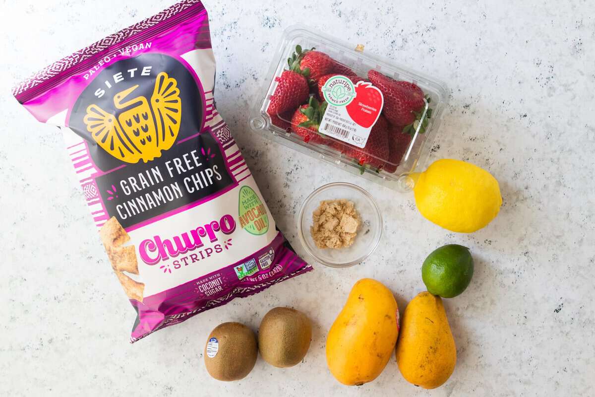 cinnamon chips, strawberries, mangos, kiwis, a lemon, lime and brown sugar displayed on a counter