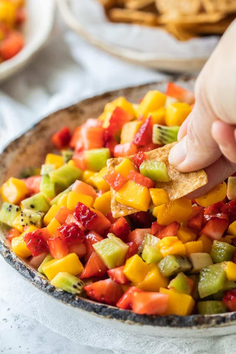 cinnamon chip scooping up fruit salsa from bowl
