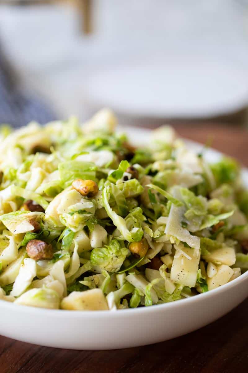 white serving bowl filled with shaved brussels sprouts