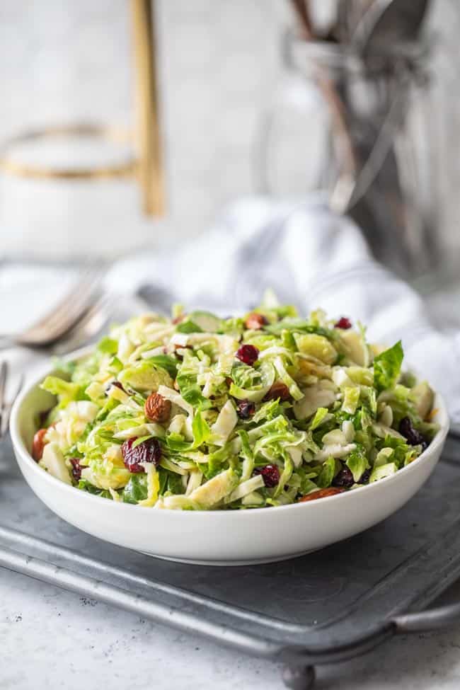 white serving bowl filled with shredded brussels sprout salad