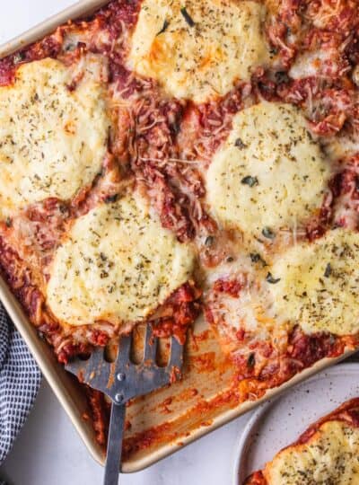 top down view of spatula scooping lasagna from sheet pan