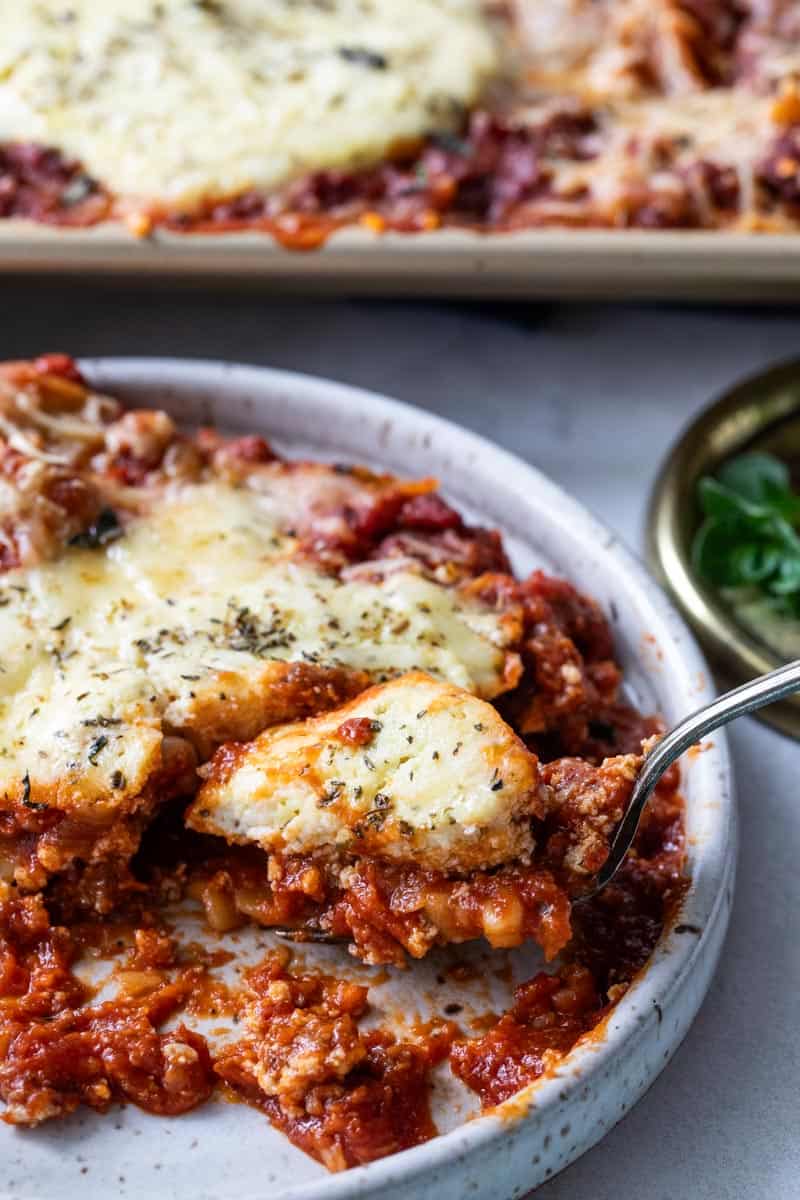 fork scooping a bite of lasagna from plate