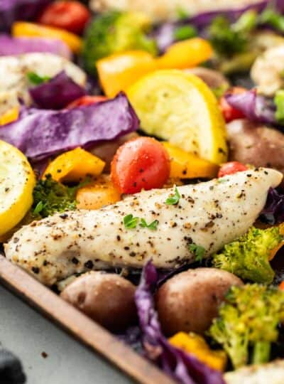 close up of baked chicken and vegetables on sheet pan