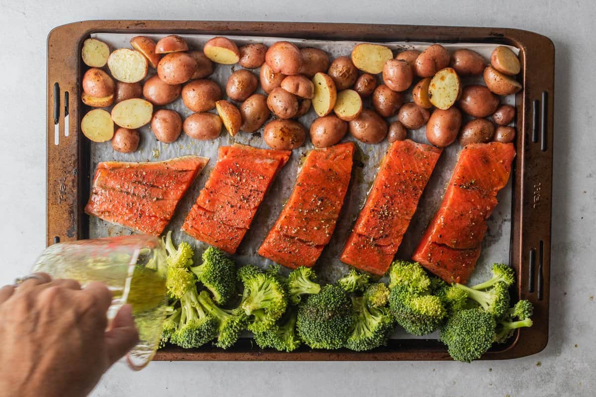 olive oil and spice mixture poured on top of broccoli florets on sheet pan