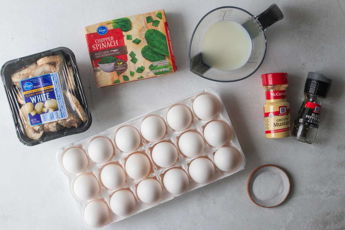 mushrooms, spinach, milk, eggs and spices on a countertop