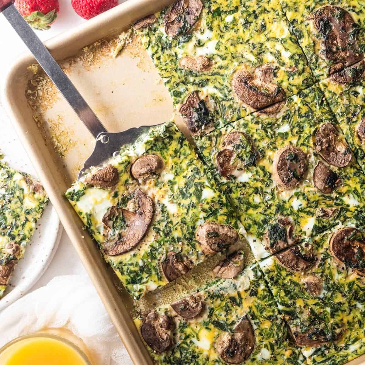 spatula scooping piece of baked eggs from sheet pan