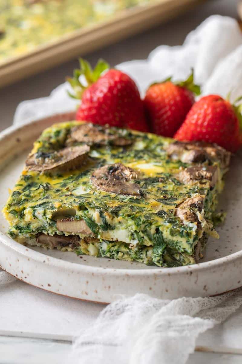 two slices of baked eggs on a plate with three strawberries