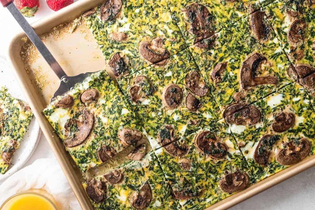 spatula scooping piece of baked eggs from sheet pan