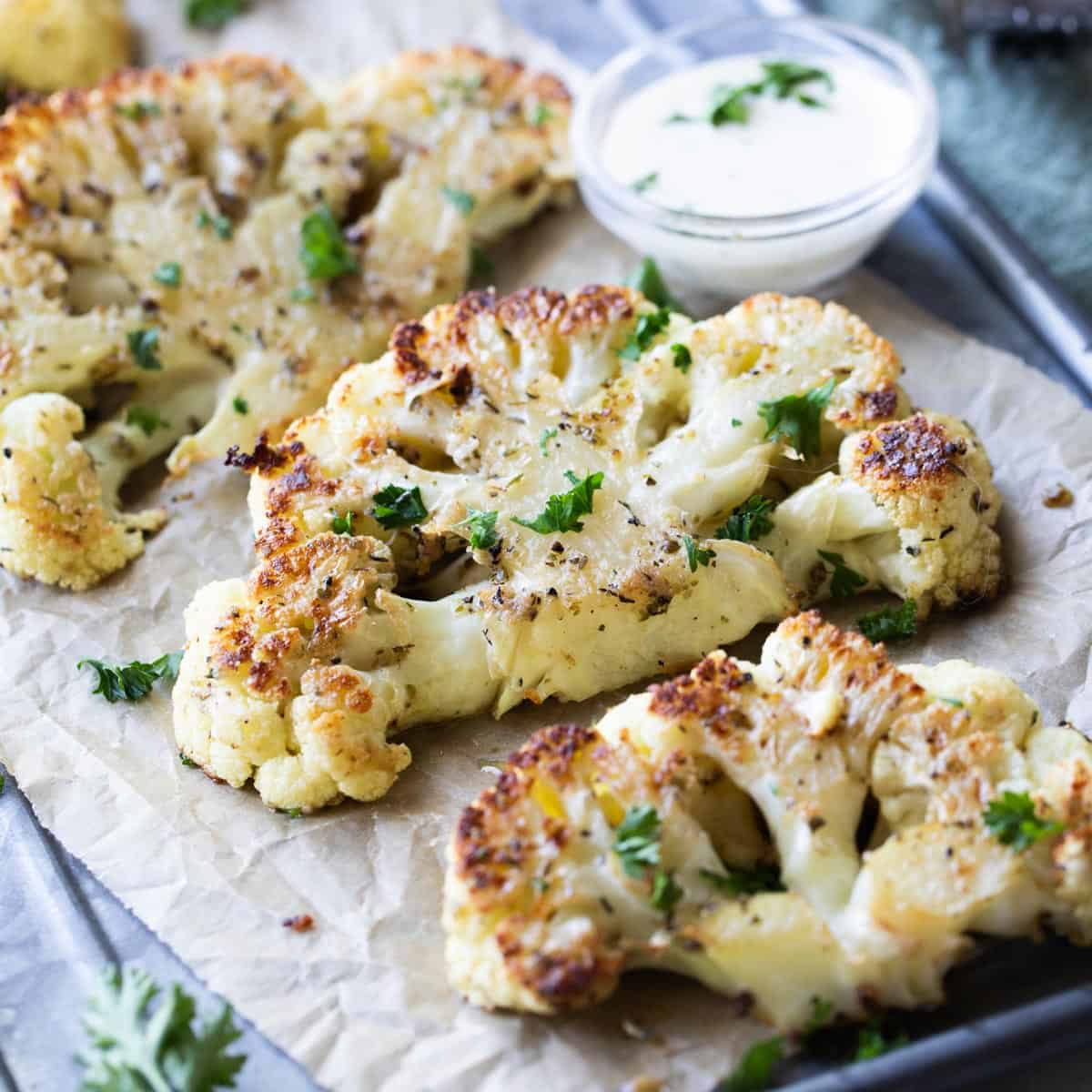 seasoned cauliflower steaks on parchment paper