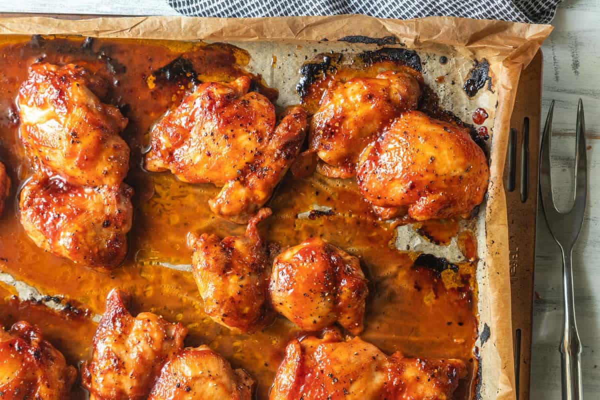 close up shot of bbq boneless chicken thighs on a sheet pan