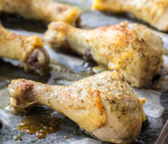 close up of baked chicken drumsticks on a sheet pan