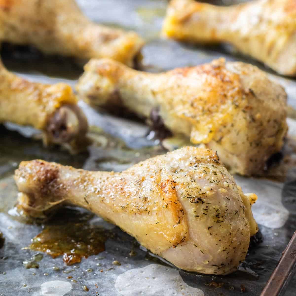 close up of baked chicken drumsticks on a sheet pan
