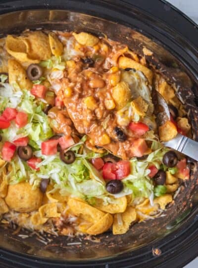 spoon in a slow cooker scooping taco casserole