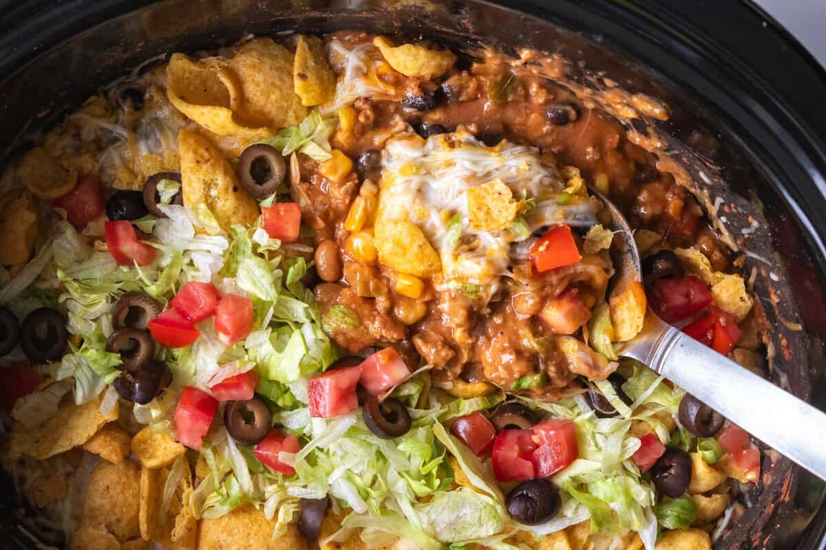 spoon in a slow cooker scooping taco casserole