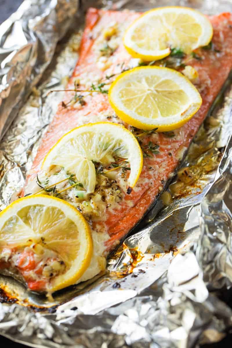 large salmon fillet topped with lemon slices on foil