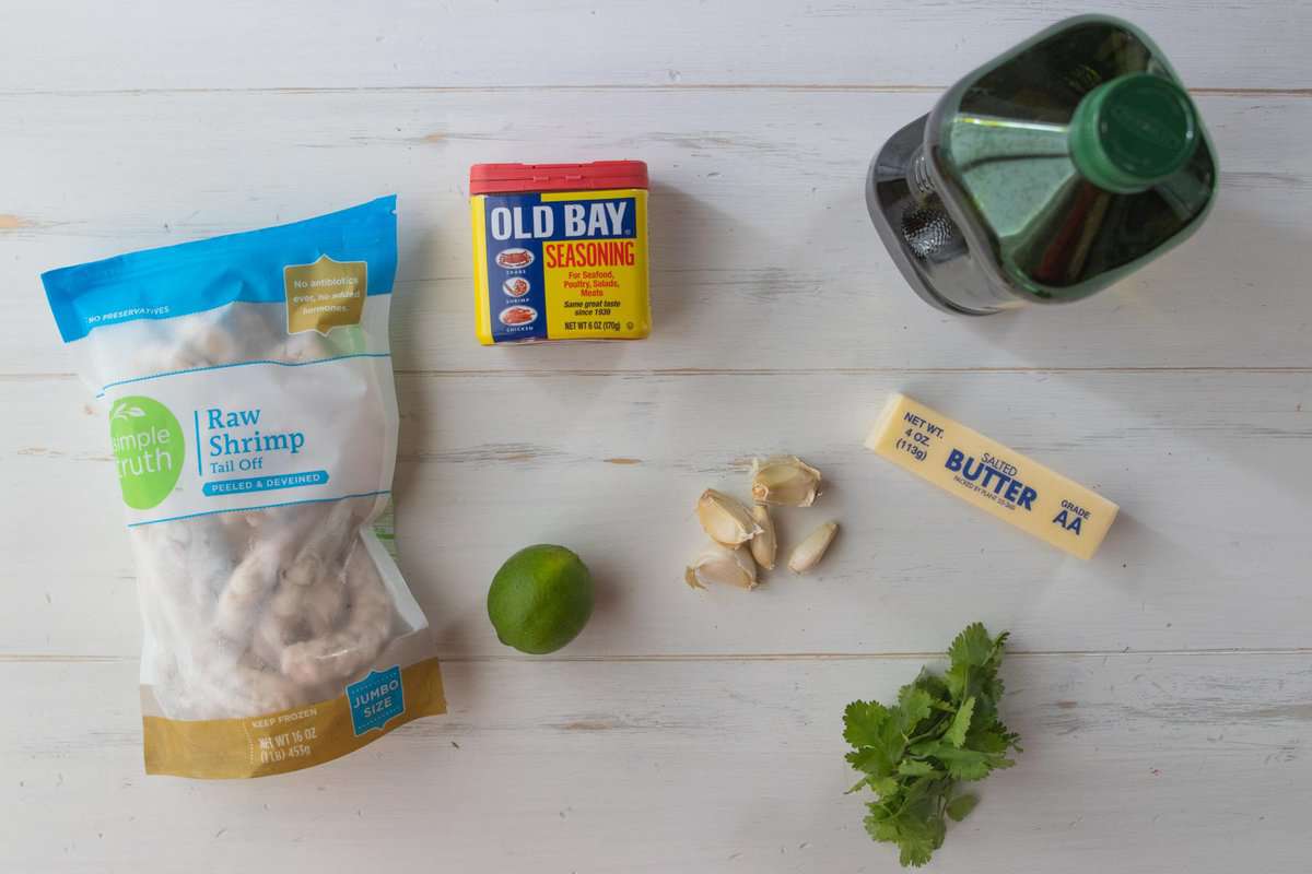 raw shrimp, old bay seasoning, olive oil, butter, garlic, lime and cilantro on countertop