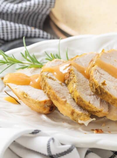slices of turkey breast on a platter drizzled with gravy