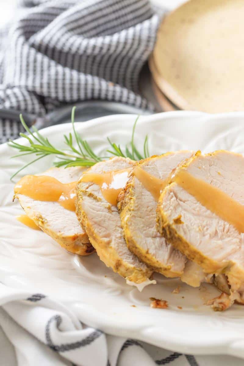 slices of boneless turkey breast on a platter drizzled with gravy