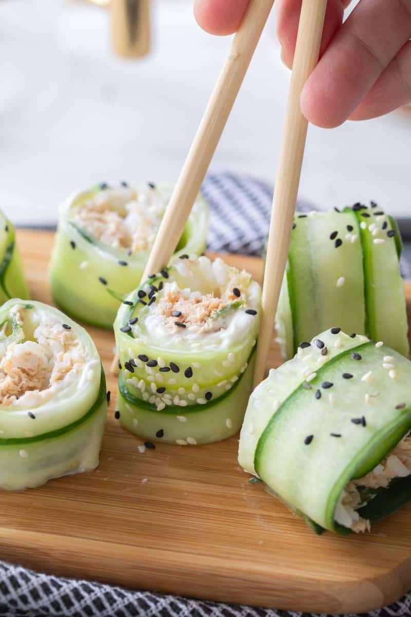 chopsticks picking up cucumber sushi rolls