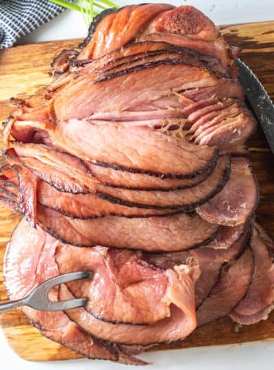 top down view of spiral ham on wooden board with carving utensils