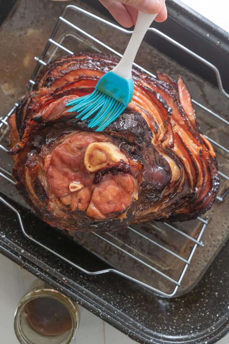 spiral ham in roasting pan being glazed