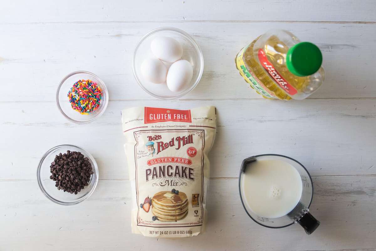 sprinkles, eggs, oil, milk, pancake mix and chocolate chips on a countertop