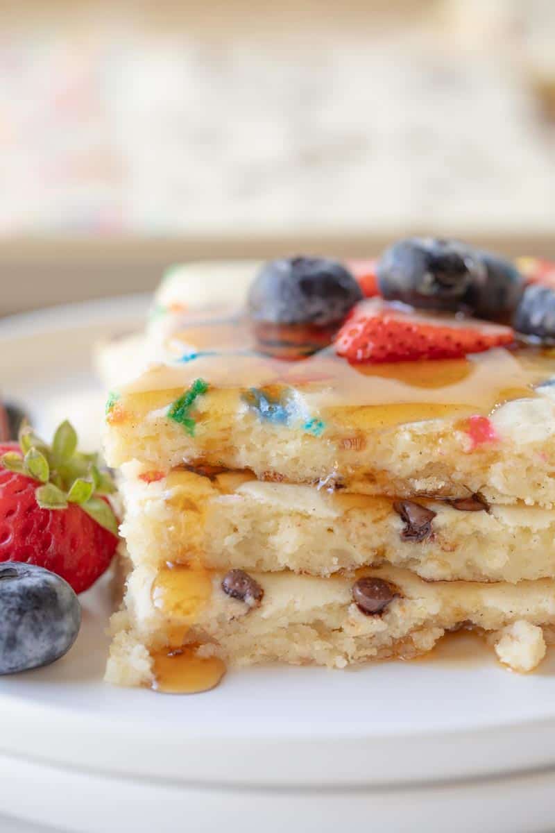 stacked pancake slices drizzled with syrup and topped with fruit