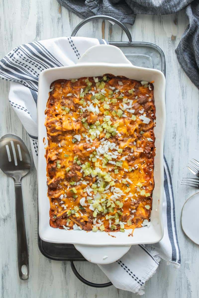 top down view of cheeseburger casserole in a baking dish topped with diced pickles and onions