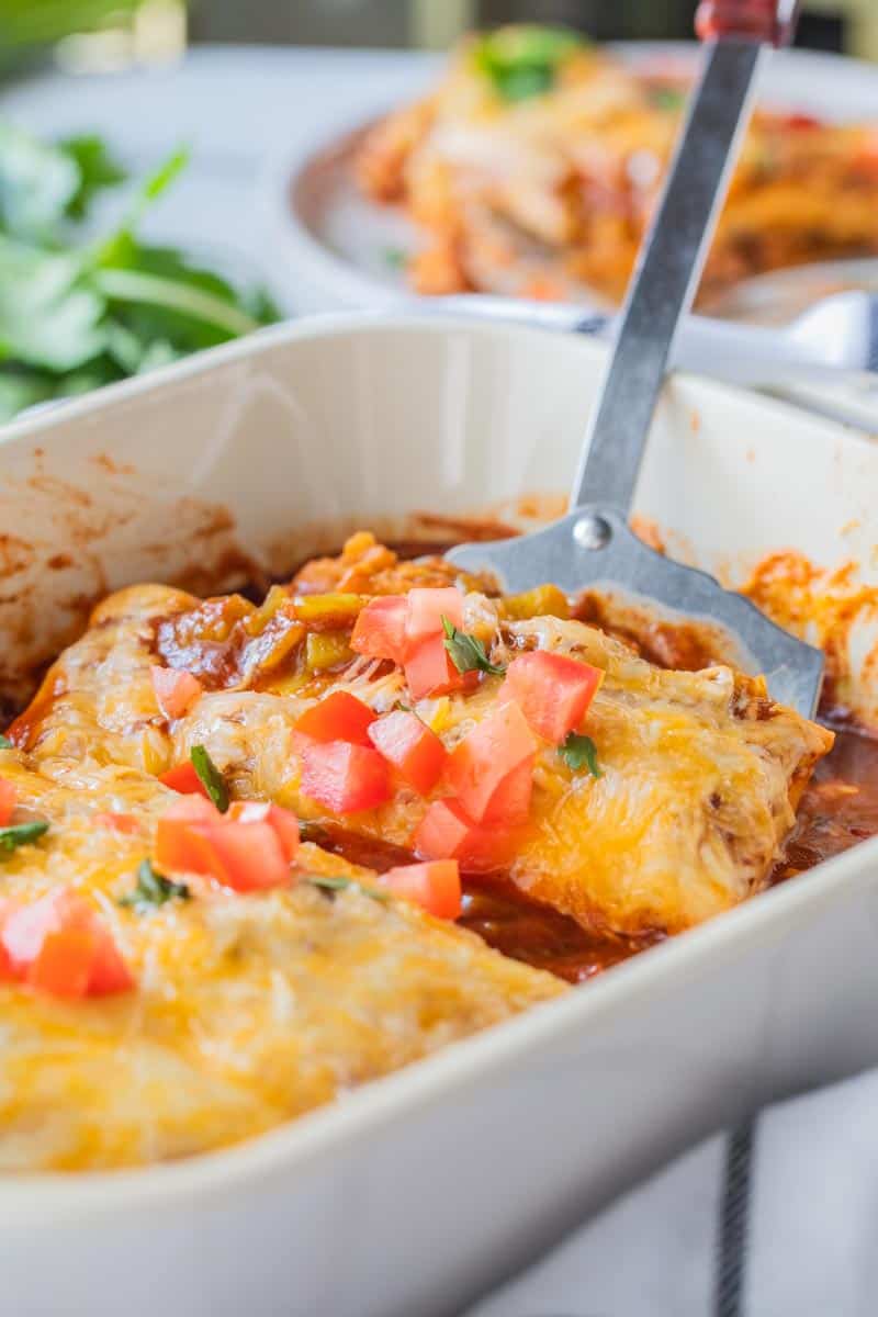 spatula scooping burrito casserole from dish