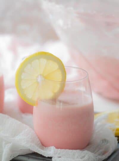 close up of pink punch in glass with lemon slice on the side