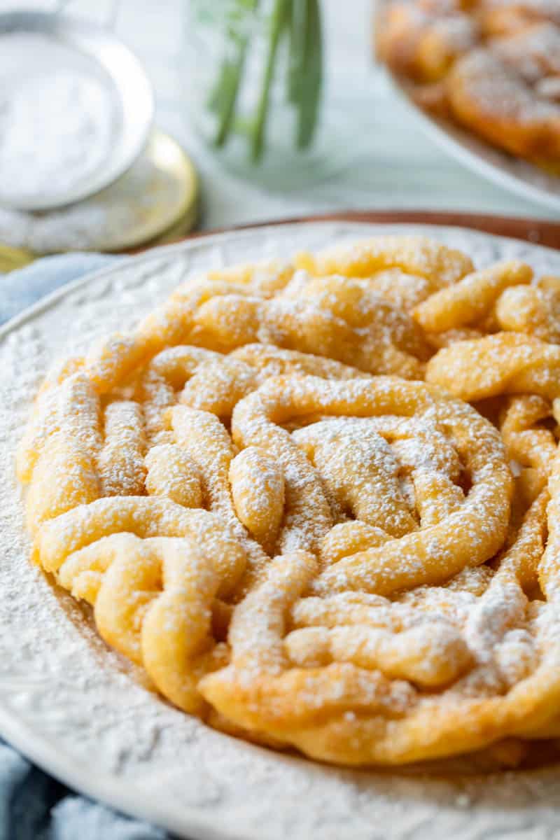 funnel cake on a plate sprinkled with powdered sugar