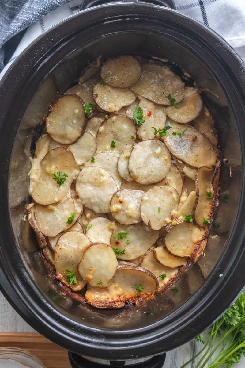 top down view of creamy sliced potatoes in a slow cooker