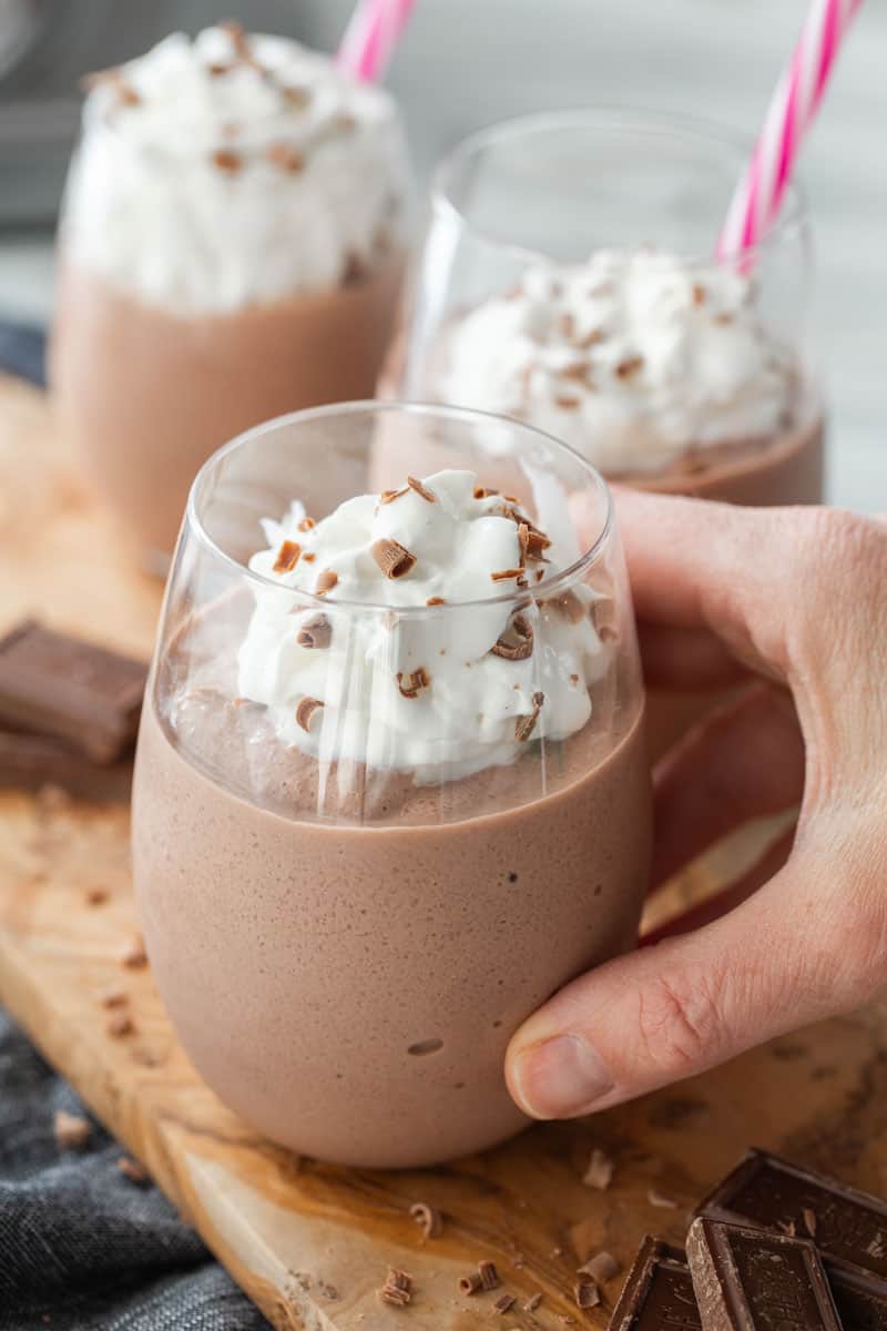 hand holding glass with frozen hot chocolate topped with whipped cream