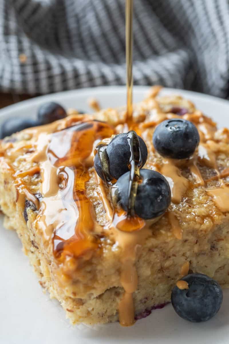 baked oatmeal slice drizzled with syrup topped with fresh berries